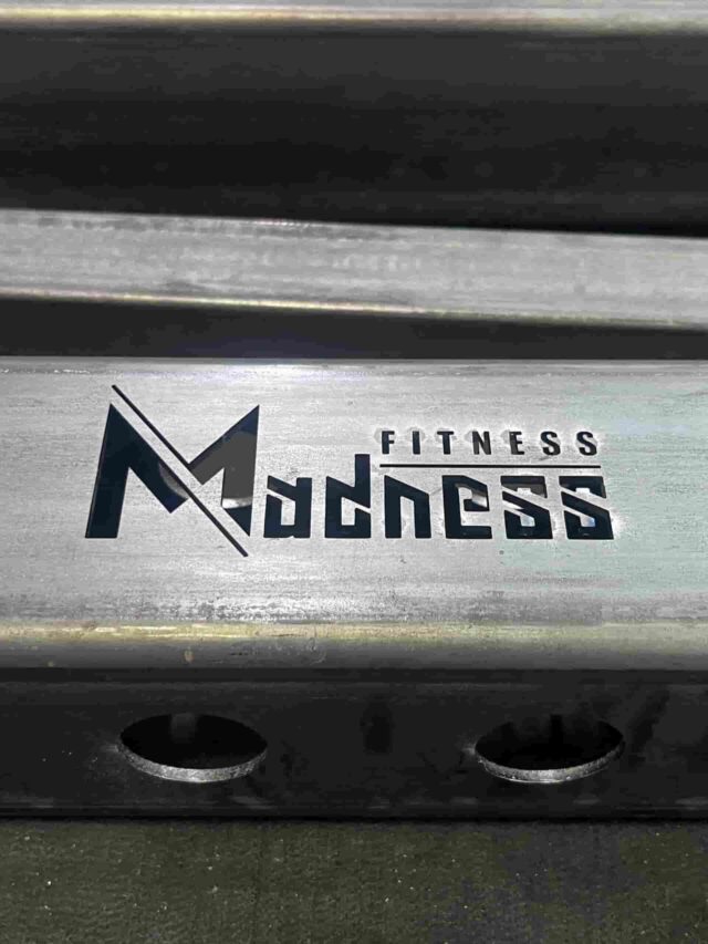 Detail laserom vyrezaného loga Fitness Madness do kovového profilu – HOSTINKOVO